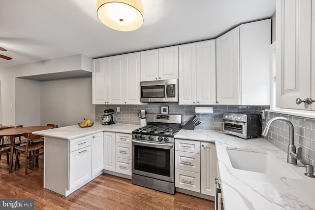 kitchen featuring a sink, stainless steel appliances, white cabinets, and light wood finished floors