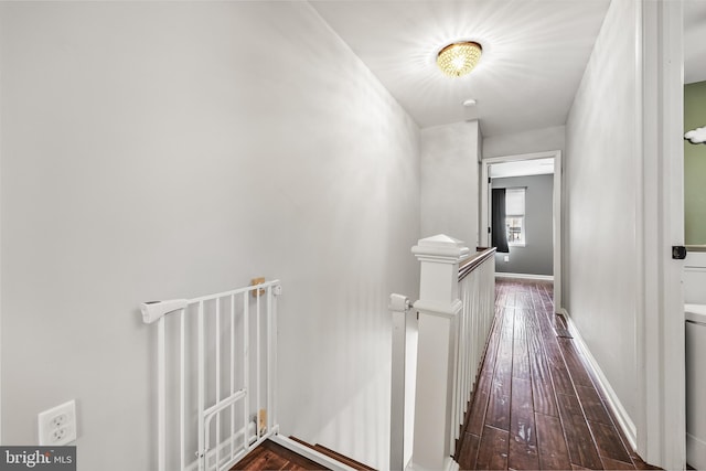 corridor with an upstairs landing, baseboards, and wood-type flooring