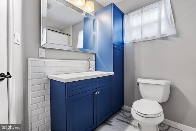 bathroom with marble finish floor, toilet, vanity, and baseboards