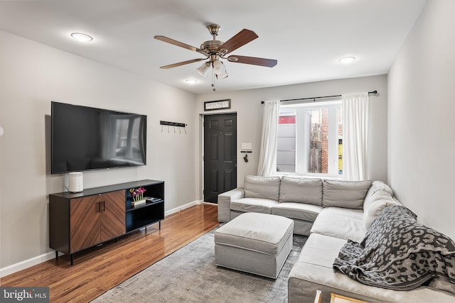 living room featuring light wood finished floors, a ceiling fan, and baseboards