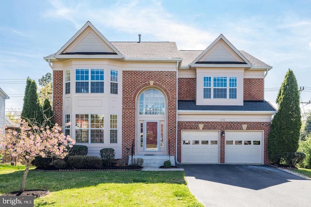 traditional home featuring aphalt driveway, an attached garage, brick siding, roof with shingles, and a front lawn