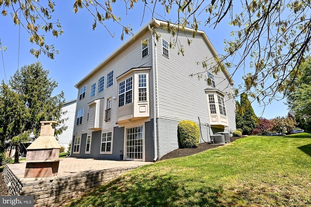 view of side of property featuring a patio area, central AC, and a lawn