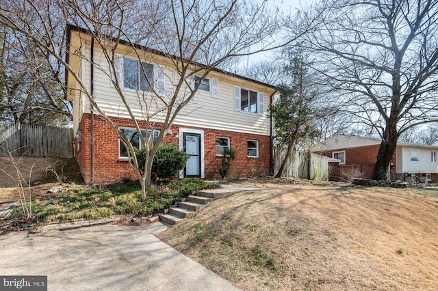 colonial-style house featuring brick siding and fence