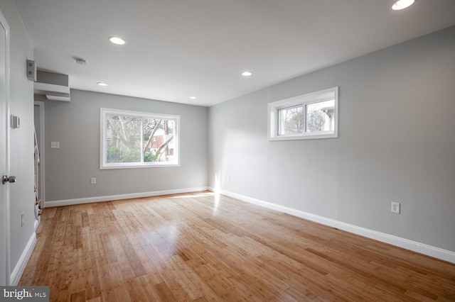 spare room featuring baseboards, a healthy amount of sunlight, and light wood-style floors