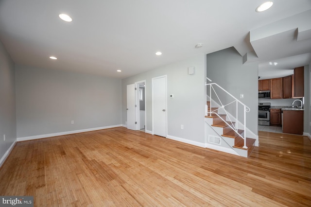 unfurnished living room with stairs, light wood-type flooring, visible vents, and recessed lighting