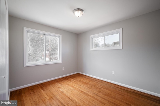 empty room featuring a healthy amount of sunlight, light wood-style floors, and baseboards