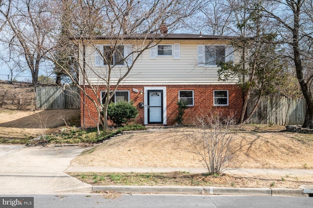 colonial inspired home with fence and brick siding