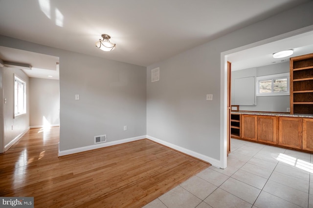 unfurnished room with light wood-style floors, baseboards, and visible vents