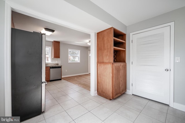 kitchen with stainless steel appliances, brown cabinets, baseboards, and light tile patterned floors