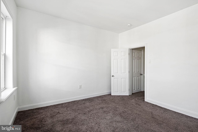 carpeted empty room featuring baseboards