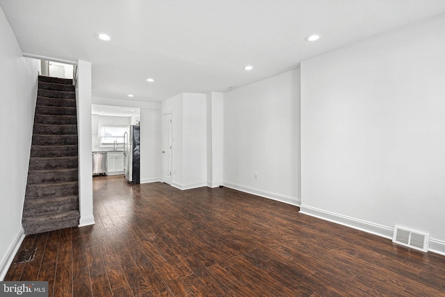 unfurnished living room with recessed lighting, dark wood-type flooring, visible vents, baseboards, and stairway