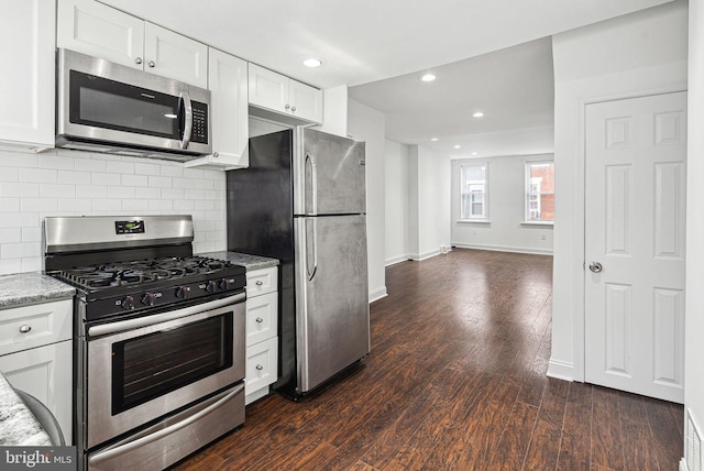 kitchen with stainless steel appliances, white cabinetry, dark wood finished floors, and light stone counters