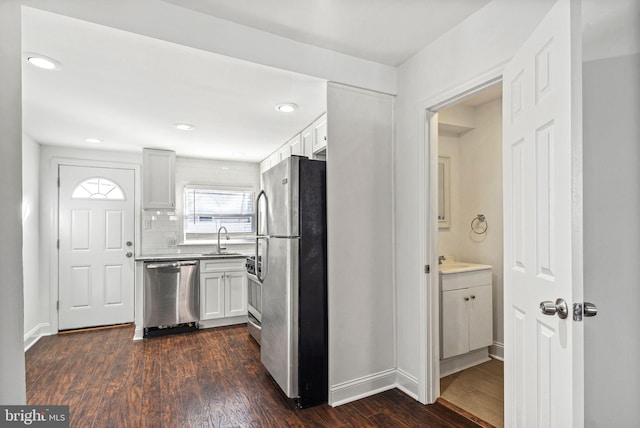 kitchen with stainless steel appliances, a sink, dark wood finished floors, and white cabinetry