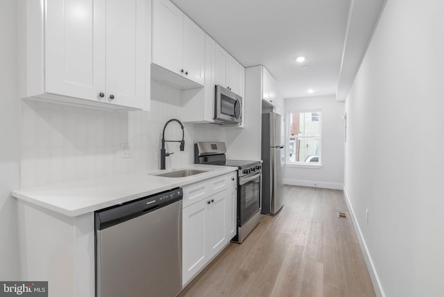 kitchen featuring stainless steel appliances, a sink, and white cabinets