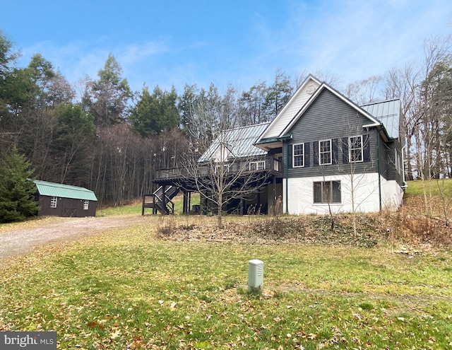 view of side of home with a standing seam roof, dirt driveway, metal roof, and a deck