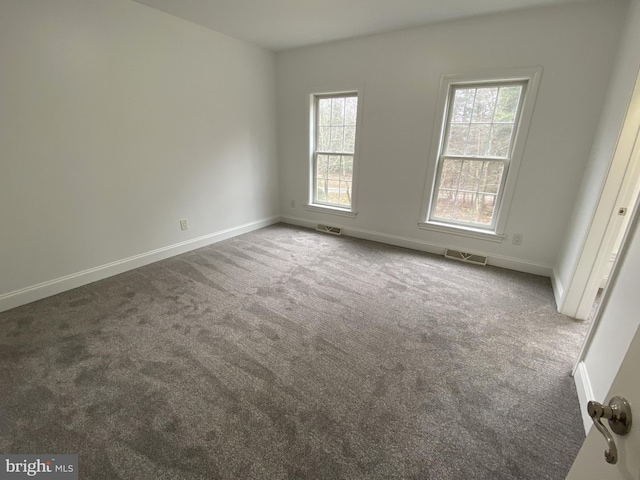 empty room with carpet flooring, visible vents, and baseboards