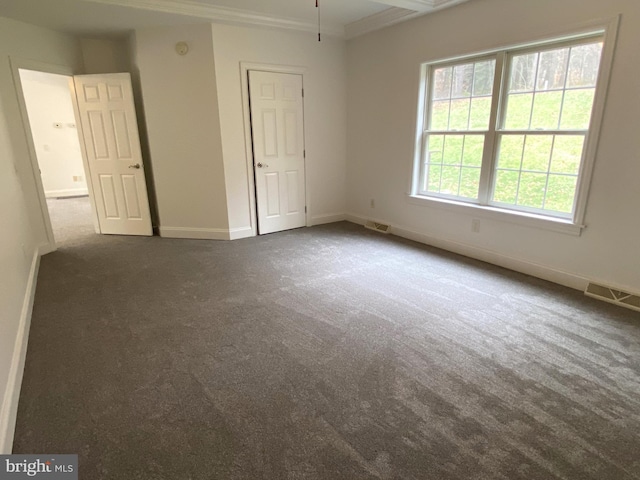 unfurnished bedroom featuring baseboards, visible vents, dark colored carpet, and crown molding