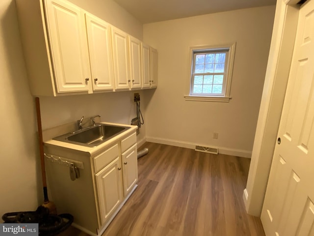 washroom featuring dark wood-style floors, washer hookup, cabinet space, a sink, and baseboards