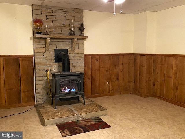 living room featuring a wood stove, a wainscoted wall, and wooden walls