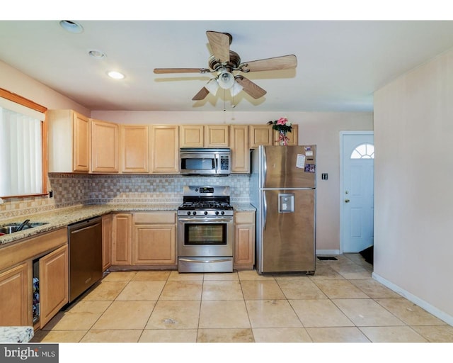 kitchen with light tile patterned floors, stainless steel appliances, tasteful backsplash, light brown cabinets, and a sink