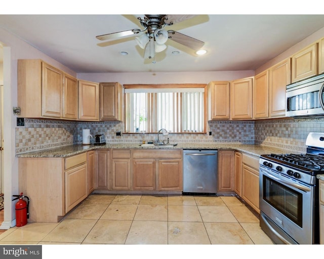 kitchen featuring stainless steel appliances, tasteful backsplash, light brown cabinetry, light tile patterned flooring, and a sink