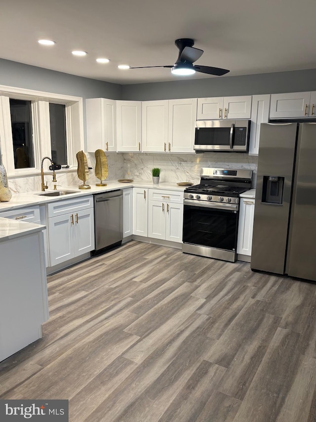 kitchen featuring light wood-type flooring, white cabinetry, stainless steel appliances, and a sink