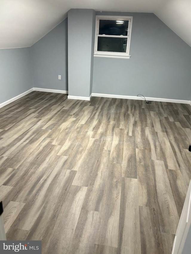 additional living space featuring lofted ceiling, baseboards, and dark wood finished floors