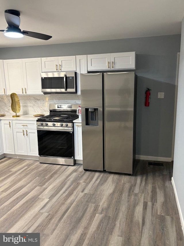 kitchen with stainless steel appliances, light countertops, white cabinetry, and light wood finished floors