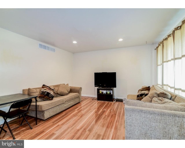 living room with light wood finished floors, visible vents, and recessed lighting