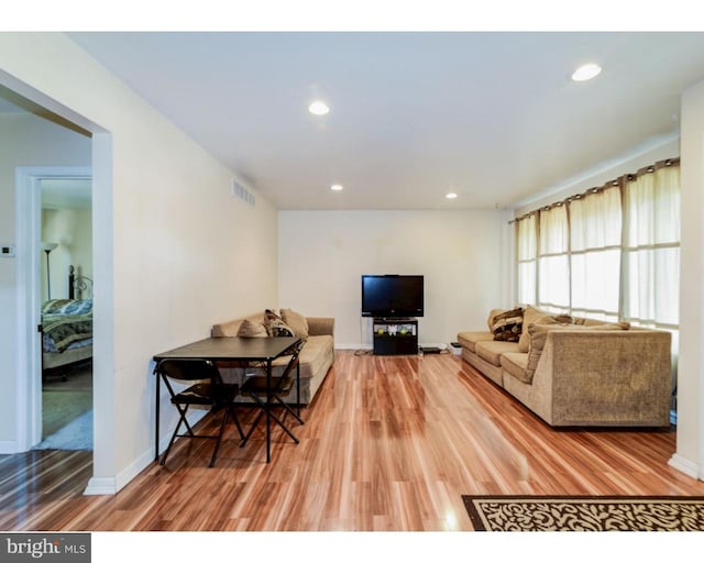 living room with light wood-type flooring, baseboards, visible vents, and recessed lighting