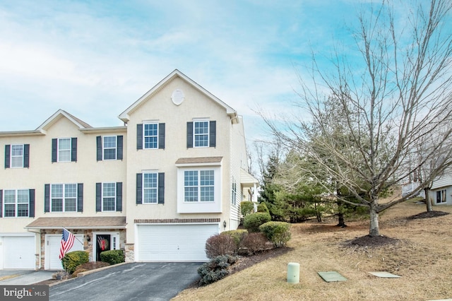 multi unit property with driveway, stone siding, a garage, and stucco siding