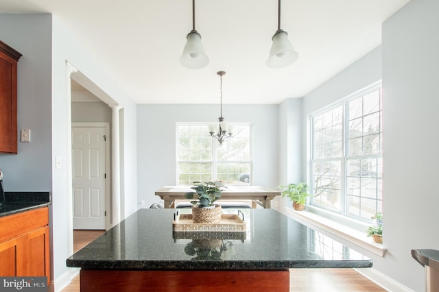 kitchen with a kitchen island, dark stone counters, pendant lighting, and a wealth of natural light