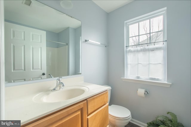 bathroom featuring toilet, walk in shower, vanity, and visible vents