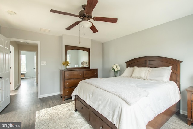 bedroom featuring ceiling fan, wood finished floors, visible vents, and baseboards