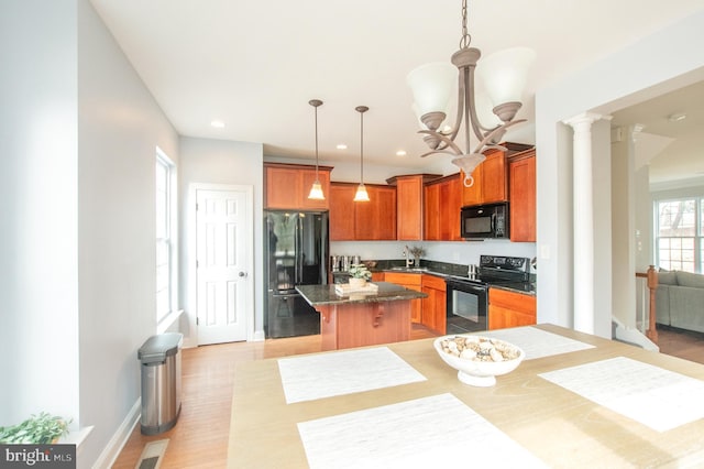 kitchen featuring decorative columns, brown cabinets, a breakfast bar, a center island, and black appliances