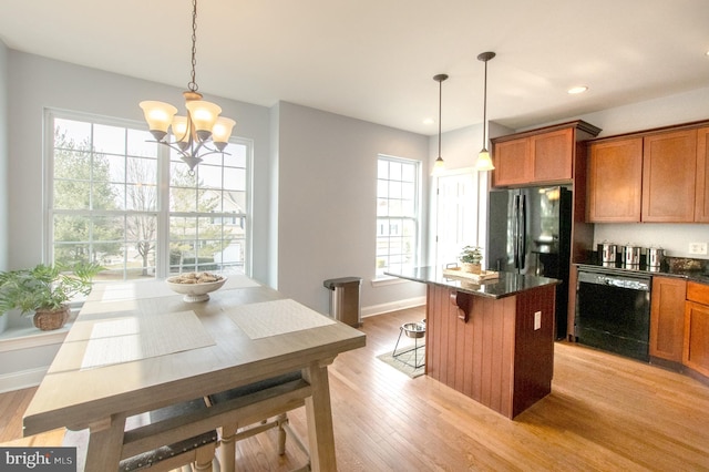 kitchen featuring black appliances, a wealth of natural light, light wood-style flooring, and brown cabinets