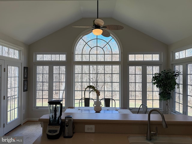 unfurnished sunroom featuring lofted ceiling, ceiling fan, and a sink