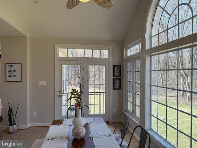 tiled dining area featuring high vaulted ceiling and baseboards