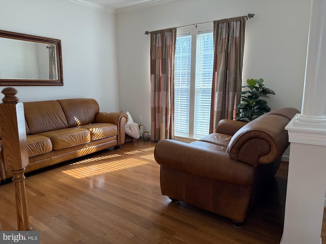 living area featuring crown molding, ornate columns, and wood finished floors