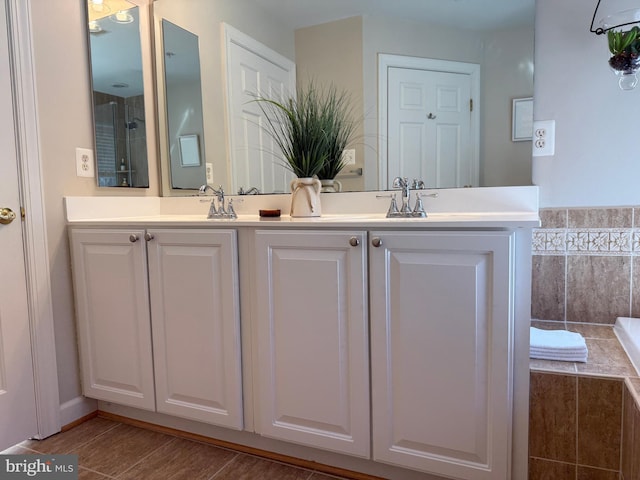 full bathroom with double vanity, a sink, and wood finished floors