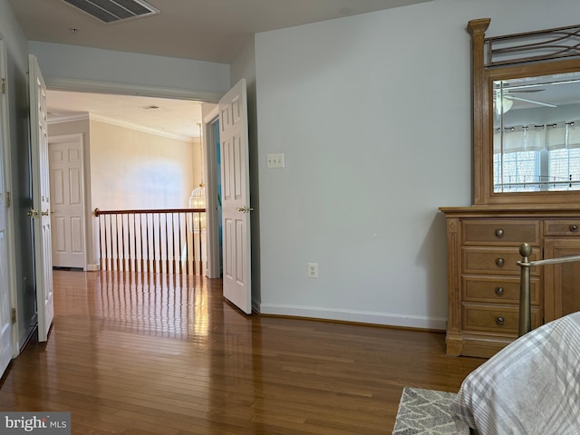 bedroom with baseboards, crown molding, visible vents, and wood finished floors