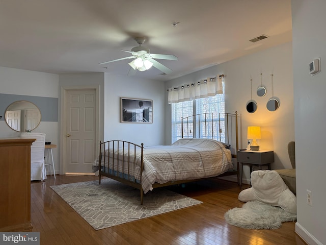 bedroom with a ceiling fan, baseboards, visible vents, and hardwood / wood-style floors