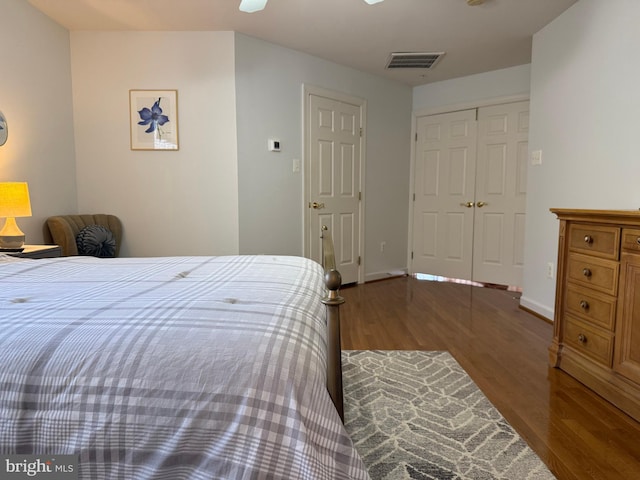 bedroom with a closet, wood finished floors, visible vents, and baseboards