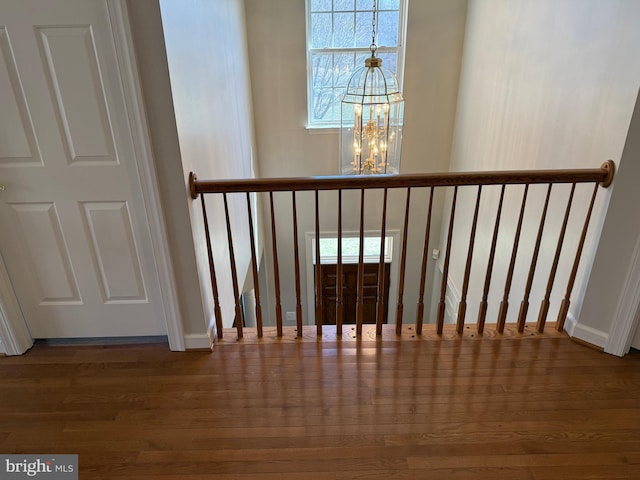 staircase with a chandelier, baseboards, and wood finished floors