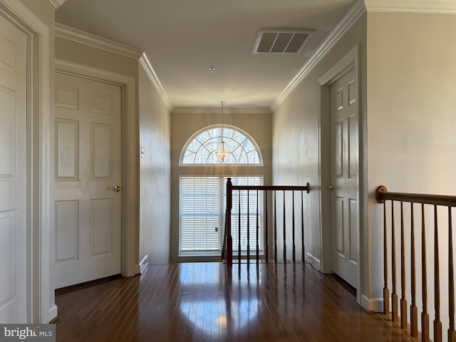 foyer entrance featuring visible vents, crown molding, baseboards, and hardwood / wood-style flooring