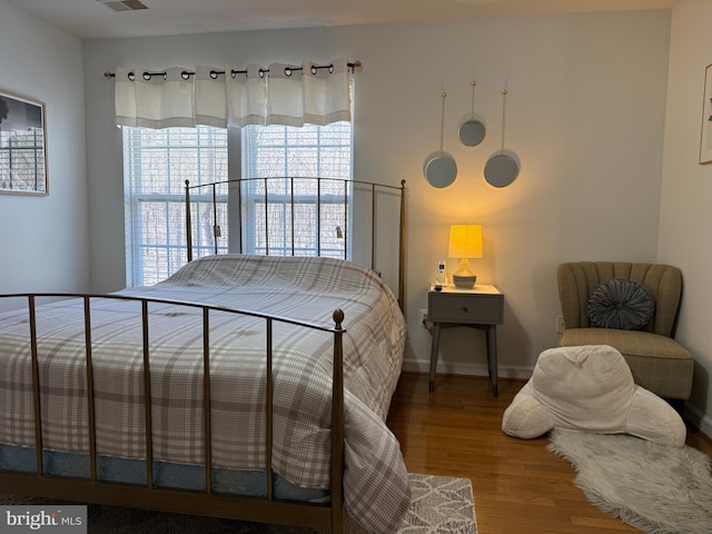 bedroom featuring visible vents, baseboards, and wood finished floors