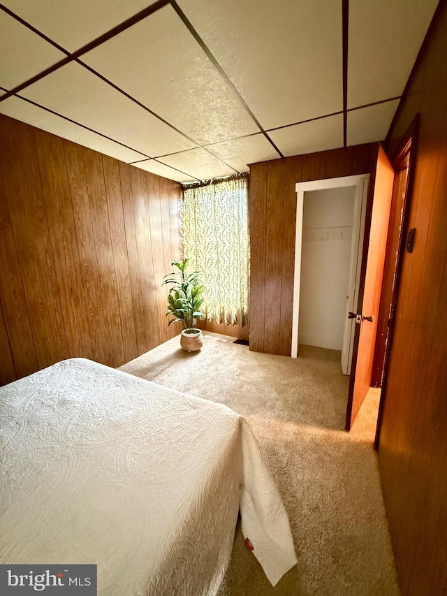 unfurnished bedroom featuring wood walls, carpet flooring, and a paneled ceiling