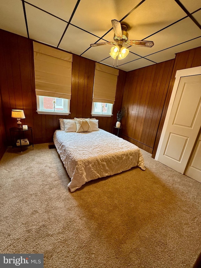 unfurnished bedroom with ceiling fan, carpet floors, and wooden walls