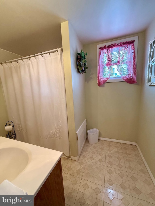 full bath featuring vanity and baseboards