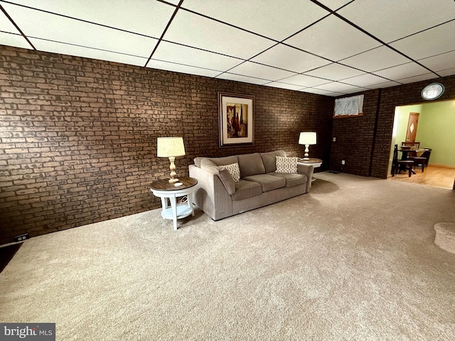 unfurnished living room with brick wall, a drop ceiling, and carpet flooring